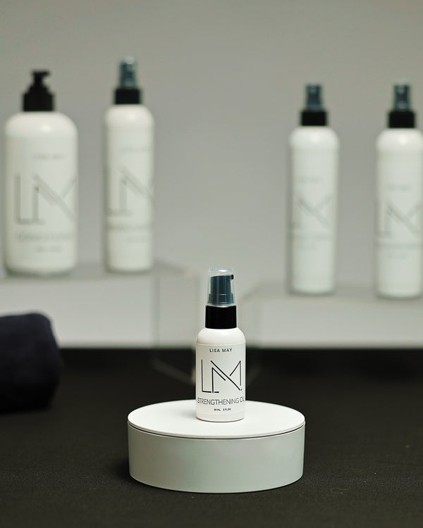 Lisa May Eco Hair Care Strengthening Oil, a small white bottle with the pump dispenser raised