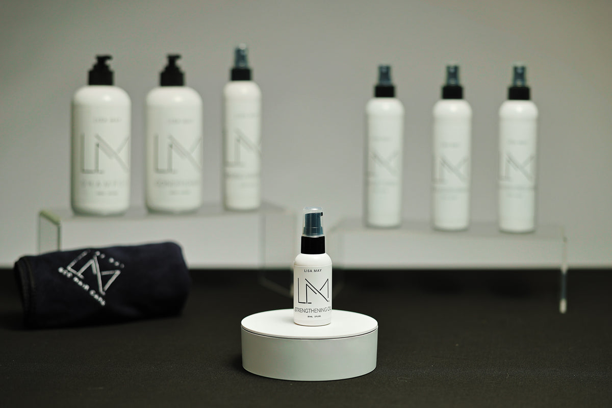 Lisa May Eco Hair Care Strengthening Oil, a small white bottle with the pump dispenser raised