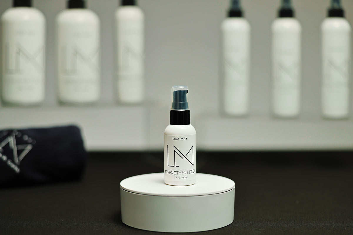 Lisa May Eco Hair Care Strengthening Oil, a small white bottle with a black pump cap